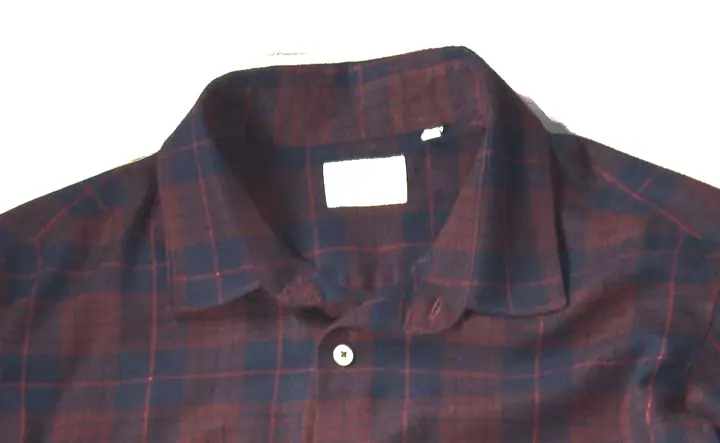 The collar and top button of the plaid shirt this page grades, under a lamp